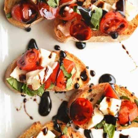 Caprese Bruschetta. Flavorful tomatoes, basil, and fresh mozzarella with a basalmic reduction drizzle.