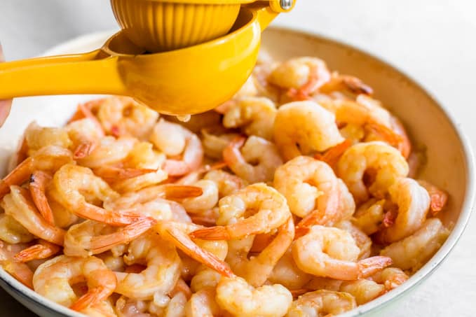 Squeezing lime juice over cooked shrimp.