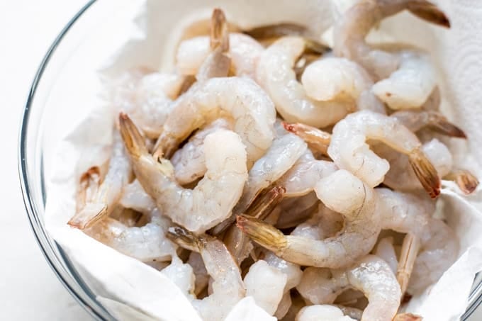 Raw shrimp in a glass bowl and paper towels.