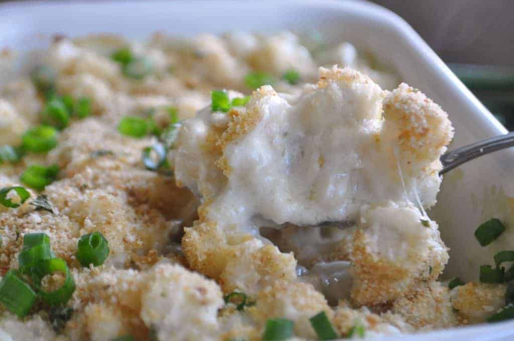 Blue cheese hominy being scooped out of the baking dish. 