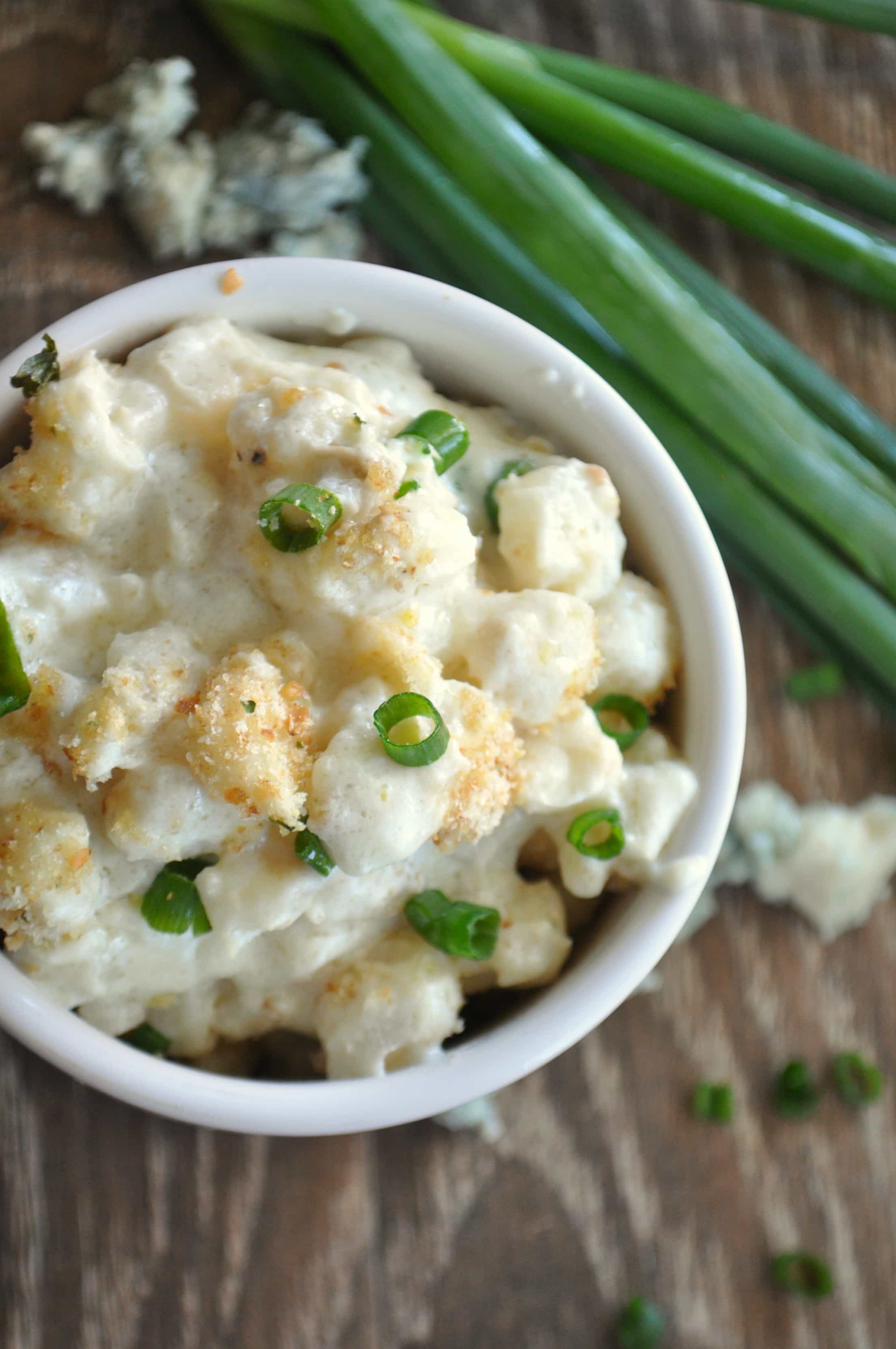 Overhead view of blue cheese hominy, showing bread crumb topping and green onion garnish. 