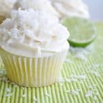 Lime cupcake topped with white coconut frosting, sprinkled with shredded coconut.