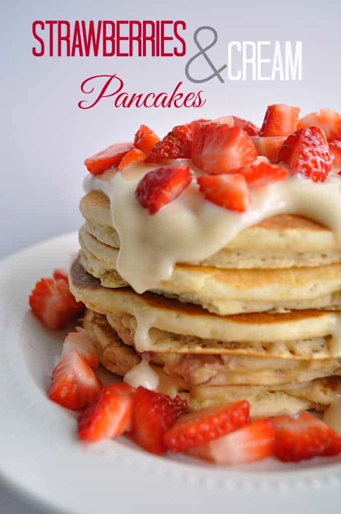 Stack of fluffy pancakes with cream cheese glaze drizzle and topped with diced strawberries.