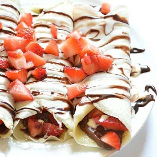 Enjoy S'mores for breakfast with this easily assembled S'mores Crepe recipe!  Crepes filled with Nutella and strawberries and topped with chocolate and marshmallow syrups.  DE-lish! 