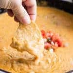 A chip dipping into homemade queso.