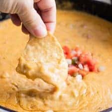 A chip dipping into homemade queso.