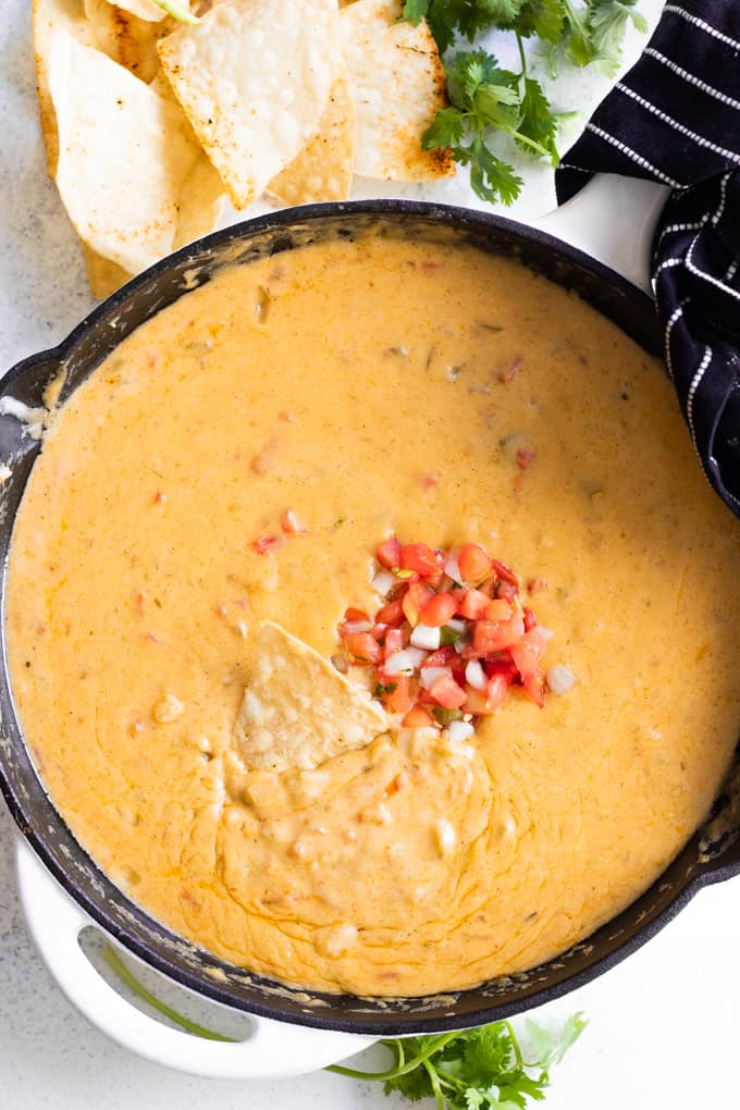 A skillet filled with homemade queso and topped with fresh pico de Gallo.