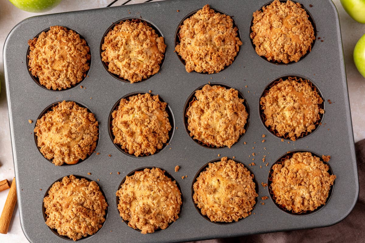 Baked apple crumb muffins in a baking tin.