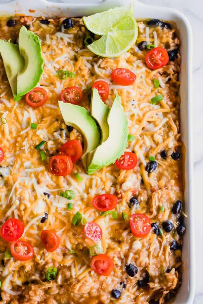 Chicken Enchilada Rice Casserole in the dish topped with tomatoes and avocado.