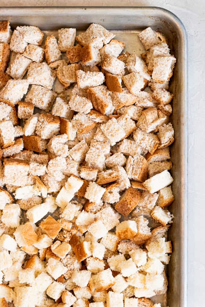 Dried breadcrumbs, cubed bread spread out on a large baking sheet, air drying, to make stuffing. 