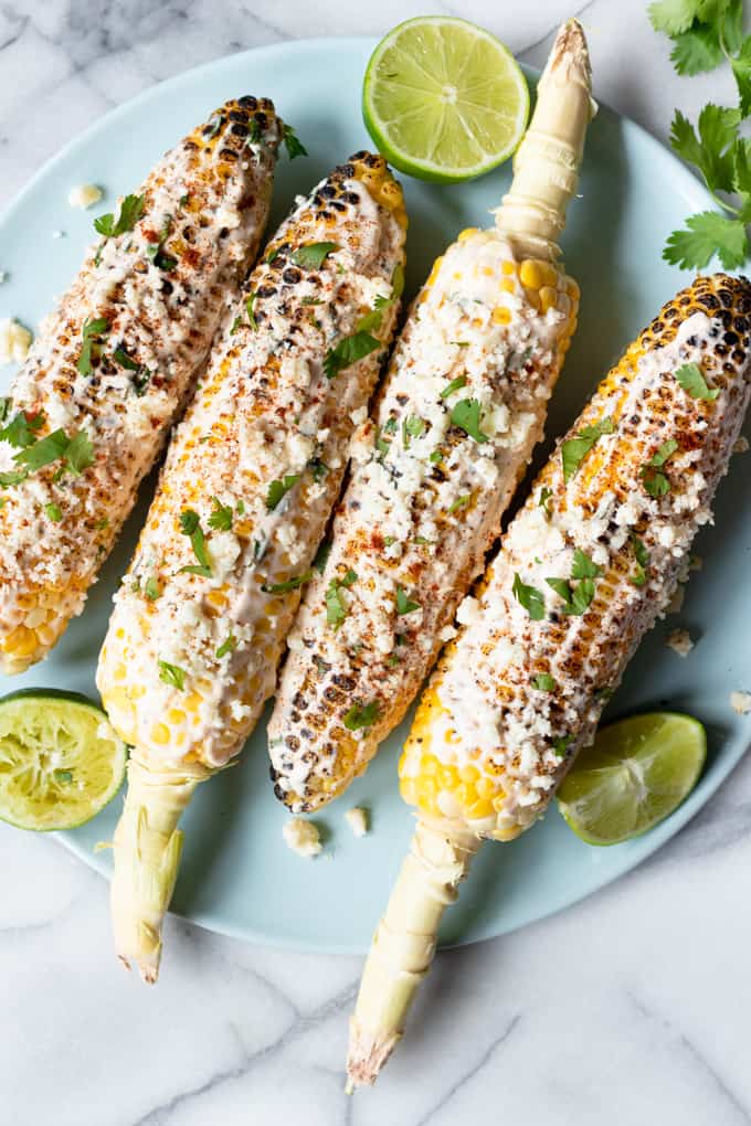 Plated Mexican Street Corn with lime wedges.