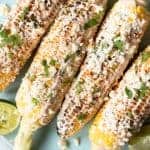 Plated Mexican street corn with lime wedges.