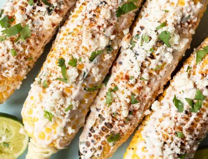 Plated Mexican street corn with lime wedges.