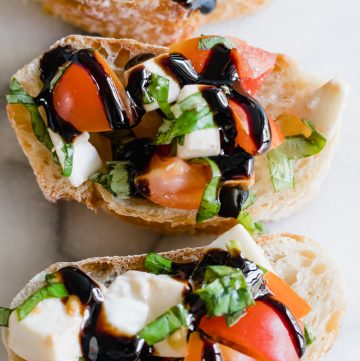 Vue de dessus d'une bruschetta au caprese arrosée d'un glaçage balsamique.