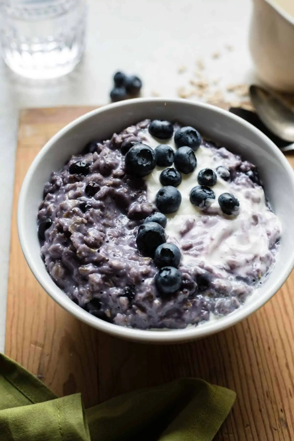 Bowl of blueberry oatmeal topped with creamy vanilla yogurt.