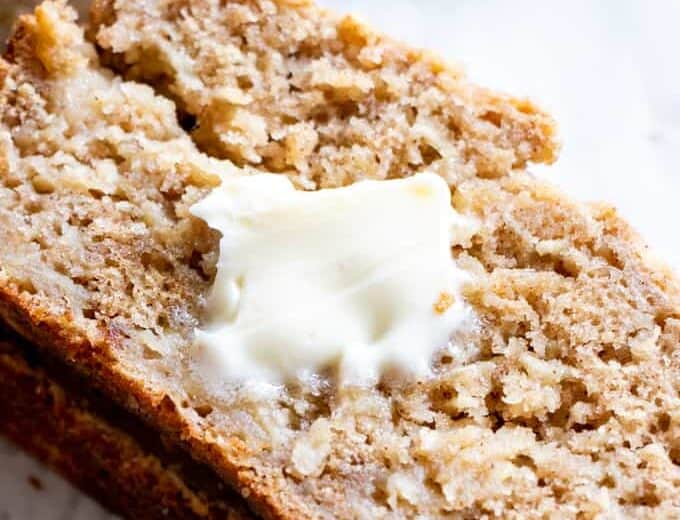 A slice of apple bread topped with a pad of melting butter.