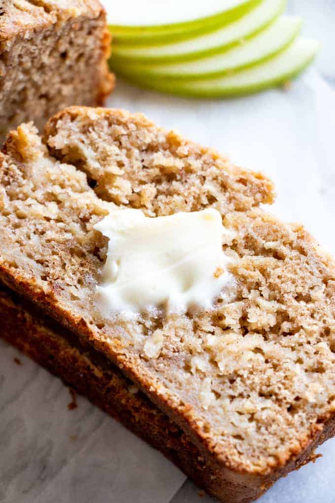 A slice of apple bread topped with a pad of melting butter.