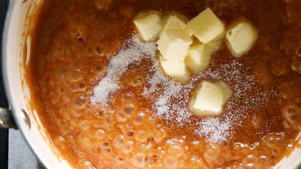 Sizzling melted sugar with butter and salt being added to make homemade caramel sauce.