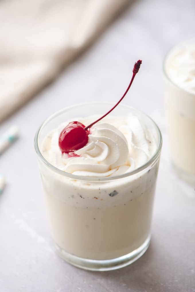 Glass filled with warm vanilla tres leches milk drink. Topped with whipped cream and a cherry.