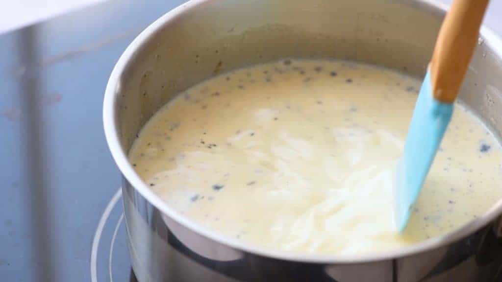 Saucepan filled with a three milk mixture and vanilla bean caviar to make a warm milk steamer drink.