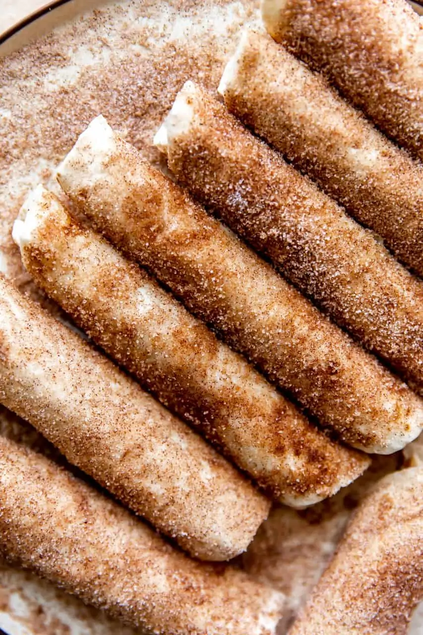 Row of cinnamon sugar tortillas laid next to each other on a plate.