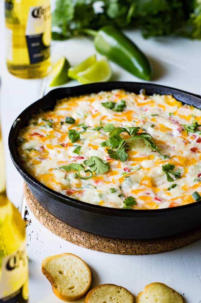 Tex Mex style Hot Pimento Cheese Dip is the ultimate in hot cheese dip recipes! Loaded with sweet pimento peppers, jalapeños, cumin, and topped with some cilantro. This cheese dip is sure to disappear FAST! 