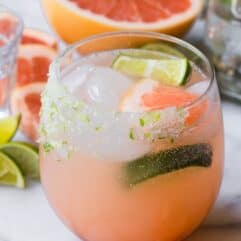 Grapefruit Paloma in a glass garnished with lime and grapefruit wedges.