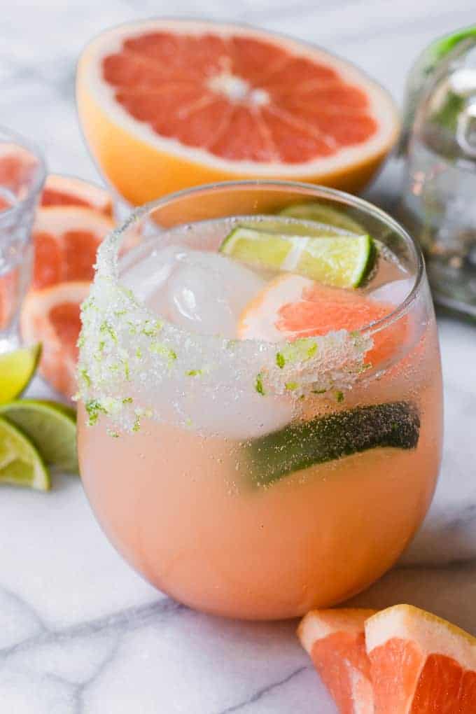 Grapefruit Paloma in a glass garnished with lime and grapefruit wedges.