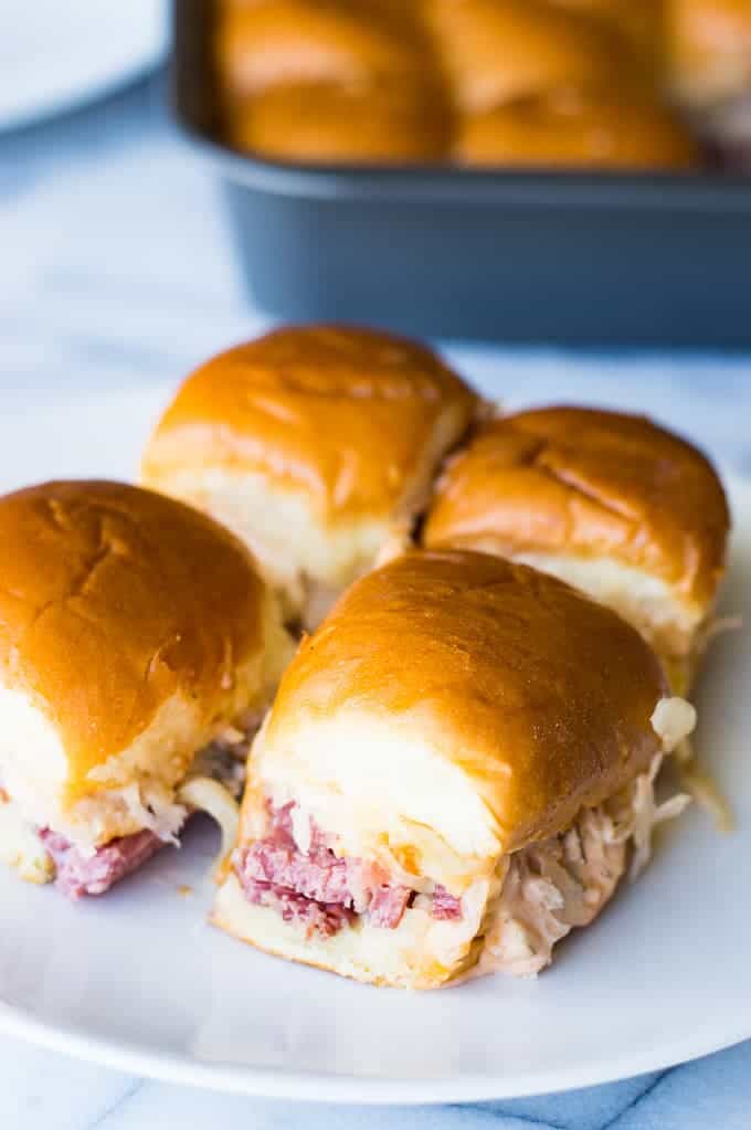Easy to make slow cooker corned beef is layered on these sliders. Topped with Swiss cheese and a homemade Russian Dressing that makes these the BEST tasting Reuben Sliders around!!