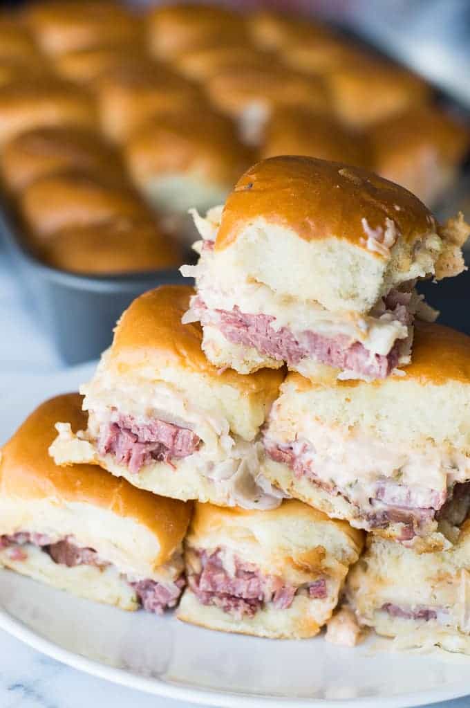 Easy to make slow cooker corned beef is layered on these sliders. Topped with Swiss cheese and a homemade Russian Dressing that makes these the BEST tasting Reuben Sliders around!!