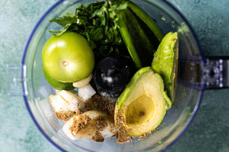 Ingredients needed for avocado salsa in a food processor.