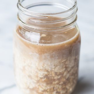 Jar filled with oats filled with almond milk and coffee.