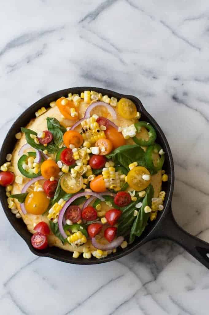 This cornbread is loaded with fresh grilled corn, cheese, and topped with farmers market finds! Tomato, jalapeño, red onion, fresh basil, and even more grilled corn! Make it your own by adding your own toppings!