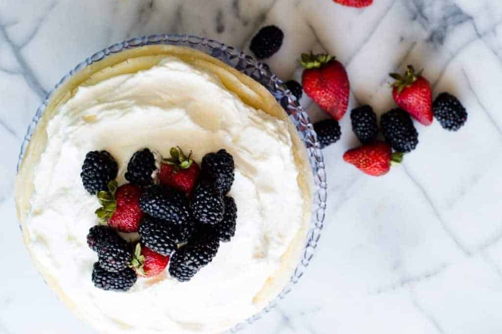 A whipped lemon mascarpone cream filling is layered with lightly sweetened crepes for a perfect dessert or brunch recipe!! Topped with lemon curd whipped cream and fresh berries! 