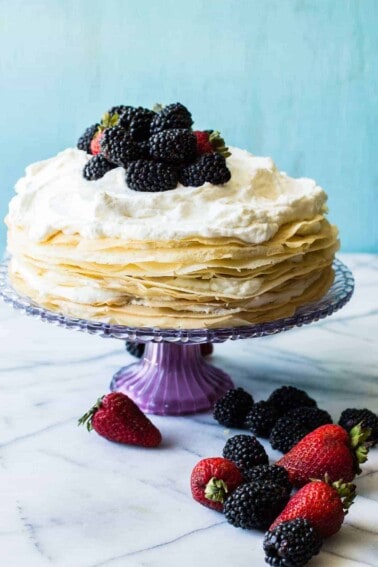 A whipped lemon mascarpone cream filling is layered with lightly sweetened crepes for a perfect dessert or brunch recipe!! Topped with lemon curd whipped cream and fresh berries!