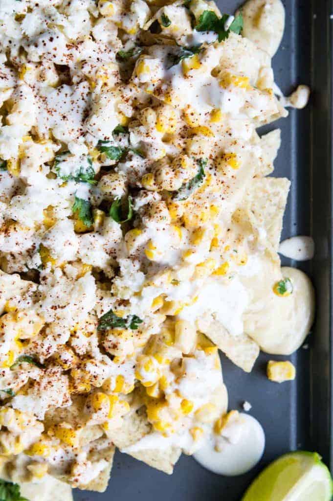 Mexican Street Corn Nachos! Chips loaded up with all the flavors of a classic mexican street corn and smothered with a creamy, spicy queso blanco.