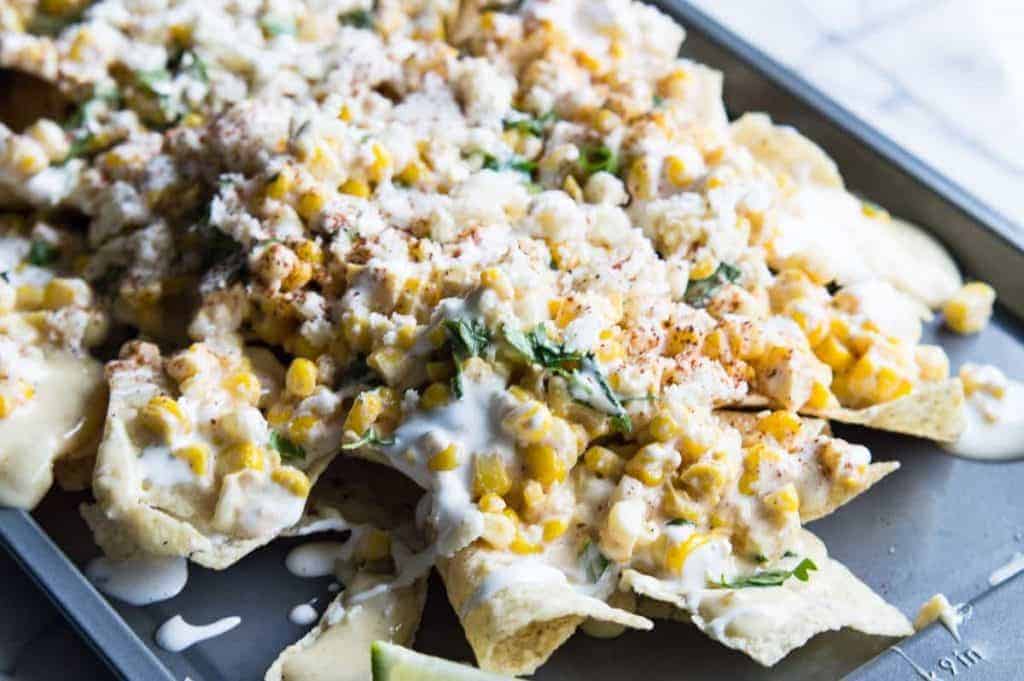 Mexican Street Corn Nachos! Chips loaded up with all the flavors of a classic mexican street corn and smothered with a creamy, spicy queso blanco.