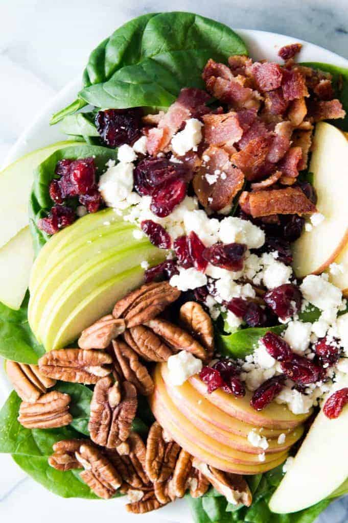 Autumn Apple Salad with a Maple Vinaigrette will let you celebrate all the flavors of Fall! Pecans, cranberries, apples, feta and baby spinach all drizzled with an easy to make maple dijon vinaigrette!