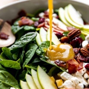 Maple Vinaigrette being drizzled over the top of an apple salad.