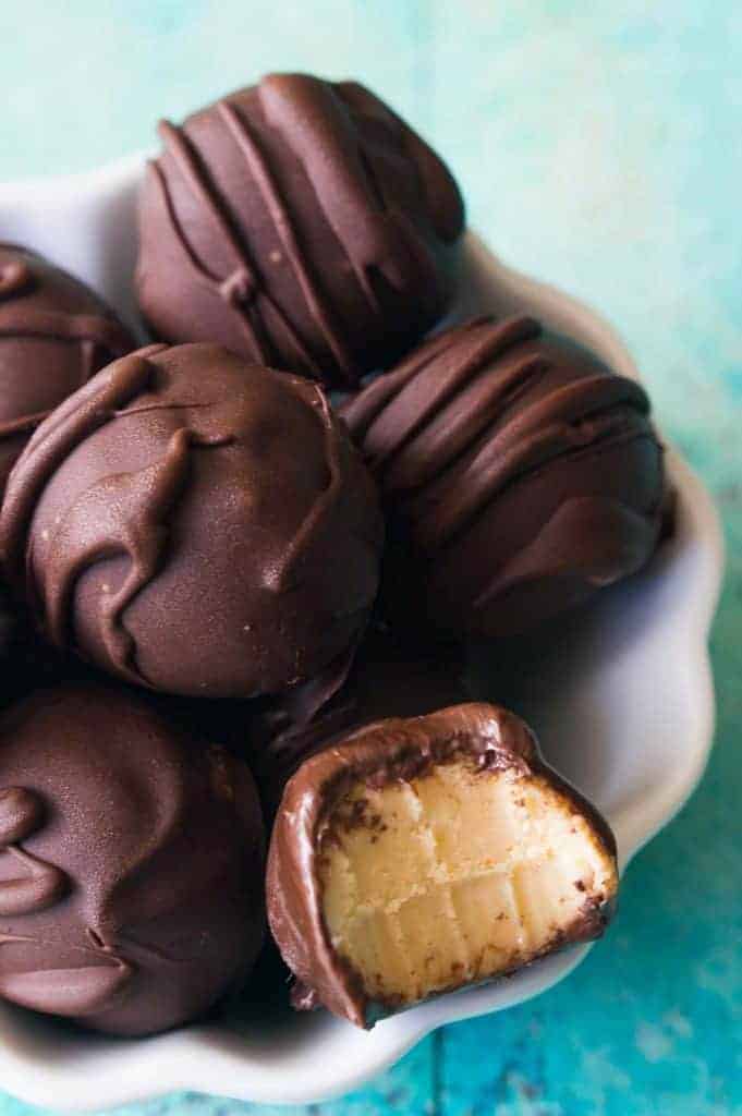 Bowl filled with pumpkin spice truffles, one with a bite missing showing how smooth and creamy they are inside! 