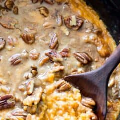 A slow cooker filled with sweet potato casserole topped with brown sugar pecan topping.