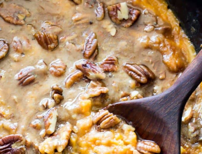 A slow cooker filled with sweet potato casserole topped with brown sugar pecan topping.