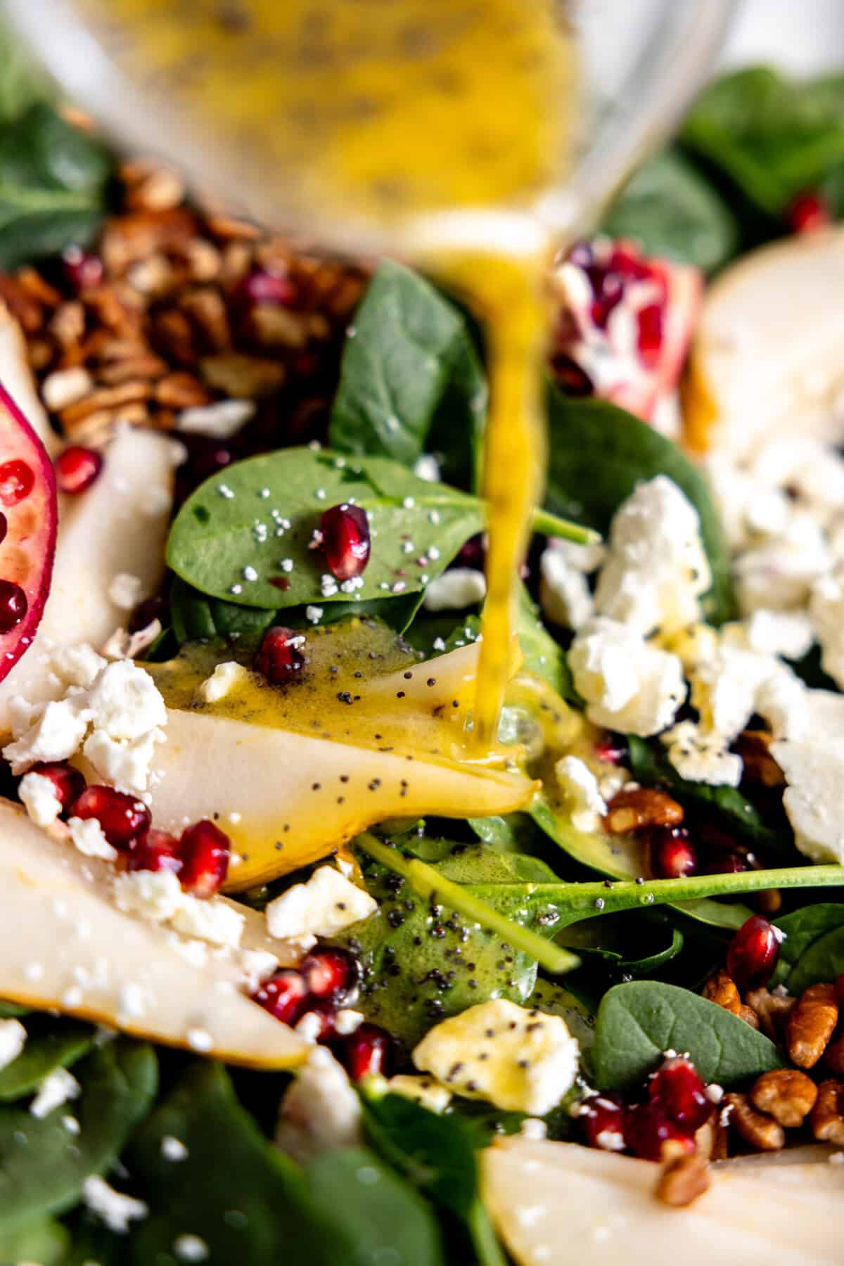 Drizzling orange poppyseed dressing on top of salad. 