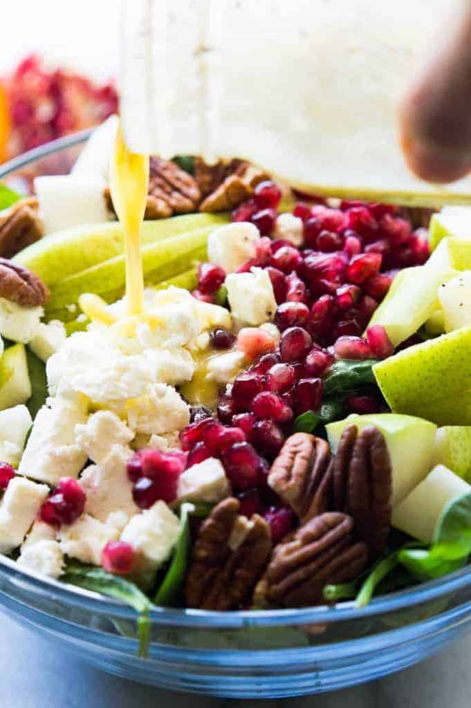 Pear & Pomegranate Salad with Orange Poppyseed Vinaigrette. This salad is loaded up with juicy pear, tart pomegranate, pecans, feta, all on a bed of fresh baby spinach and drizzled with a citrus orange poppyseed vinaigrette. This beautiful salad will be the highlight of any meal! The colors are perfect for any Holiday spread too! 