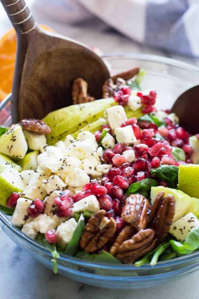 Pear & Pomegranate Salad with Orange Poppyseed Vinaigrette. This salad is loaded up with juicy pear, tart pomegranate, pecans, feta, all on a bed of fresh baby spinach and drizzled with a citrus orange poppyseed vinaigrette. This beautiful salad will be the highlight of any meal! The colors are perfect for any Holiday spread too! 