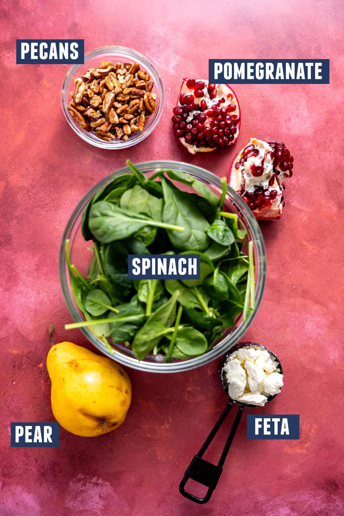 Ingredients needed to make a Christmas salad with spinach and pomegranate laid out on the counter. 