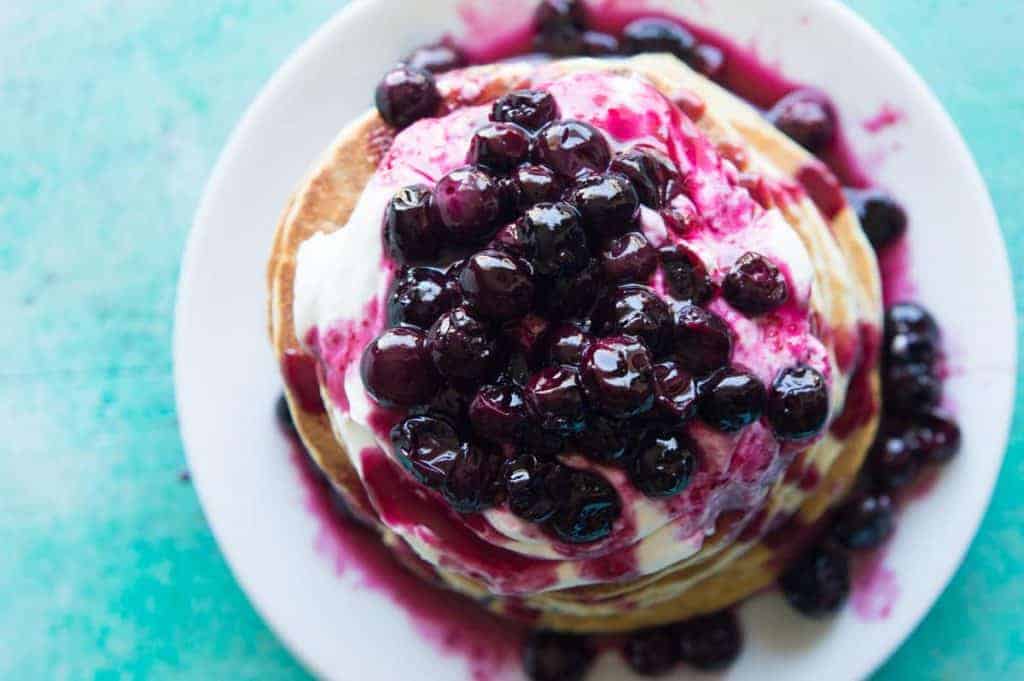 Blueberry Cheesecake Pancakes! Soft pancakes bursting with juicy blueberries. Topped with a fluffy cheesecake topping and a homemade blueberry sauce. You will want to start everyday with this breakfast! Life just doesn't get any better.