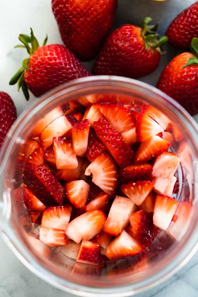 A cup filled with diced strawberries to make homemade strawberry lemon pound cake.