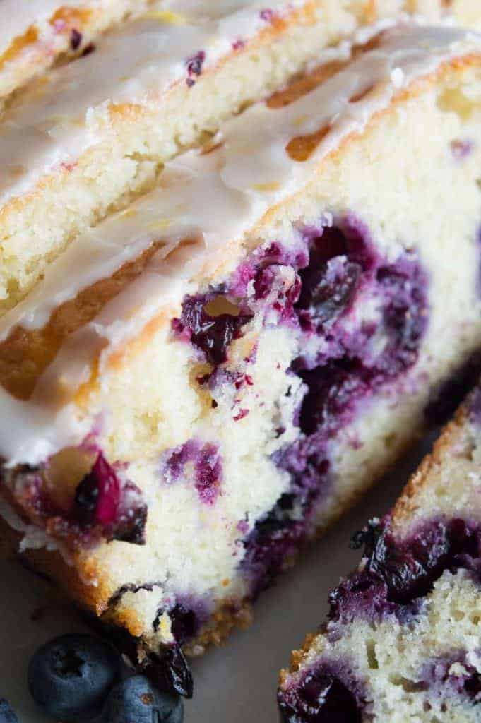 Blueberry Lemon Pound Cake! This pound cake is made lighter by using greek yogurt, and is loaded up with lemon flavor thanks to zest and fresh lemon juice! Juicy blueberries are baked right in. All drizzled with a luscious lemon glaze. 
