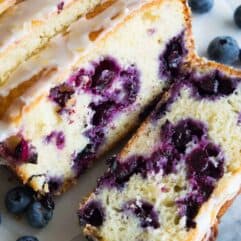 Blueberry Lemon Pound Cake! This pound cake is made lighter by using greek yogurt, and is loaded up with lemon flavor thanks to zest and fresh lemon juice! Juicy blueberries are baked right in. All drizzled with a luscious lemon glaze.
